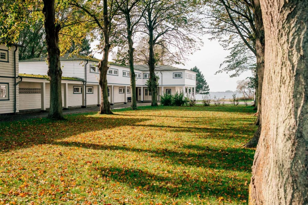 Die Mutter-Kind-Kur-Klinik und Vater-Kind-Kur-Klinik in der Natur mit Bäumen, im Hintergrund die Ostsee