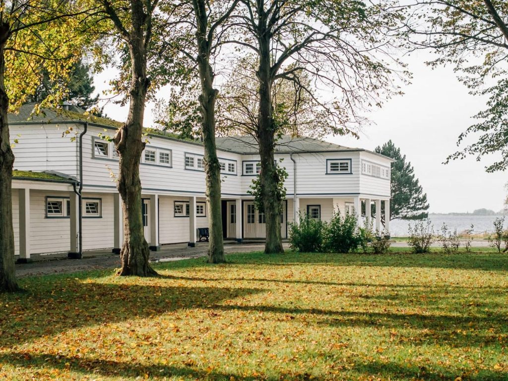 Die Mutter-Kind-Kur-Klinik und Vater-Kind-Kur-Klinik in der Natur mit Bäumen, im Hintergrund die Ostsee